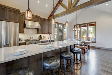 Amazing modern and rustic luxury kitchen with vaulted ceiling and wooden beams, long island with white quarts countertop.