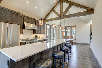 Amazing modern and rustic luxury kitchen with vaulted ceiling and wooden beams, long island with white quarts countertop.