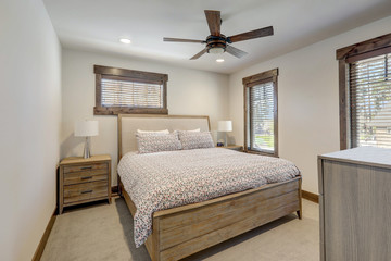 Fototapeta premium Natural tones cozy bedroom interior with grey bedding, beige carpet and lots of windows.