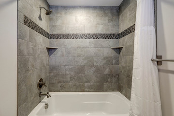 White new tub details with curtain and grey tiles.