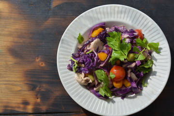 fresh salad purple color with chicken and green vegetables in white bowl on the black  wooden table
