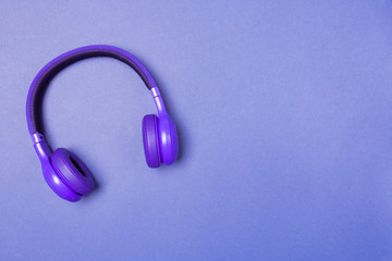 Purple headphones on purple background, top view. Copy space. Space for text. 