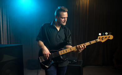 Male guitarist playing an electric bass guitar