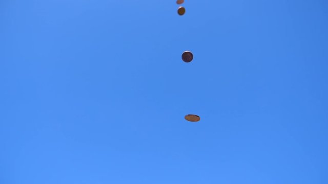 Low Angle Shot Of Many One Penny Or 1 Cent Coins Falling In A Slow Motion Against Blue Sky.