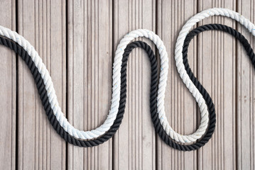 Obraz premium Black and white nautical ropes curving together outdoors on a wooden background