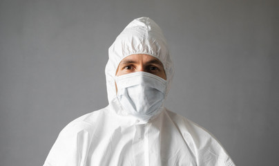 Doctor in white protective suit, medical mask and rubber gloves is ready for helping a people while coronavirus pandemic threat. Epidemic, pandemic of coronavirus covid 19. Doctor in respirator.