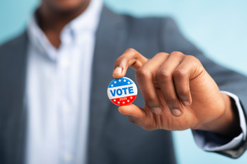 African man holding vote button on blue background