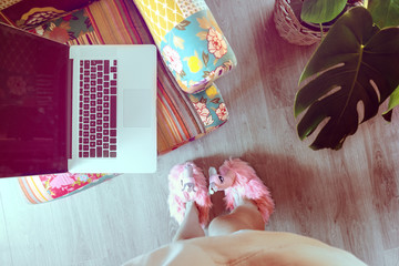 Naklejka na ściany i meble Home workspace: girl in slippers working on her laptop.