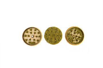 Top down studio shot of yellow metal grinder and round pile of well grinded green dried marijuana. Cannabis use preparation. Grind cannabis buds oan grinder isolated on white background