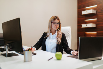 
Young beautiful caucasian businesswoman with glasses working in her office on a computer. Business and technology