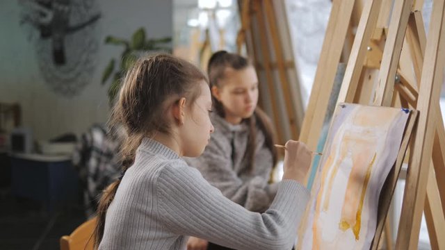 Two girls in art school to paint still life with acrylic paints.