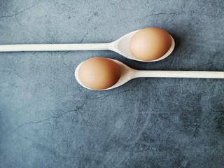 Fresh chicken eggs in wooden spoon on dark background. Easter background. Minimal style. Copy space. 