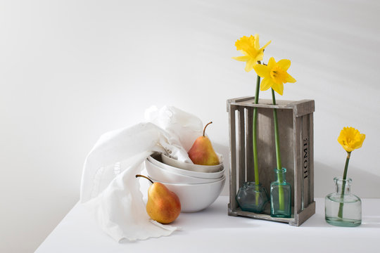 the narcissus and two pears in an inverted grey wooden decorative box on a white background