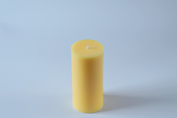 Tall yellow wax candle on white.