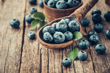 Blueberries in wooden spoon on old wood table. Healthy eating and nutrition concept.