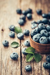 Freshly picked blueberries in wooden bowl on wooden background. Healthy eating and nutrition.