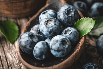 Blueberries in wooden spoon on old wood background. Healthy eating and nutrition concept.