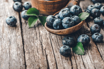 Blueberries in wooden spoon on old wood background. Healthy eating and nutrition concept.