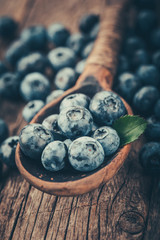 Blueberries in wooden spoon on old wood background. Healthy eating and nutrition concept.