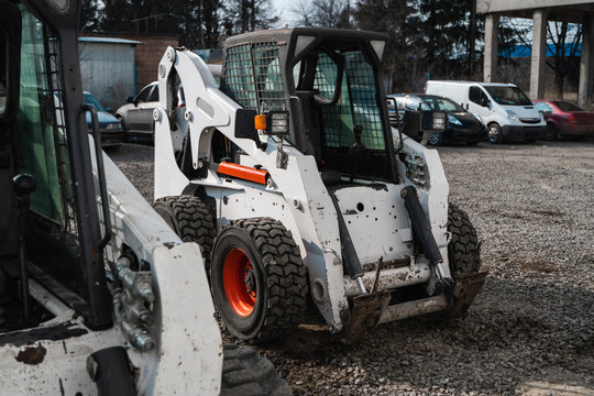 Two white skid steer loader at a construction site waiting of work. Industrial machinery. Industry.