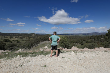 Fototapeta premium Young boy standing on cliff edge admiring view of the landscape below