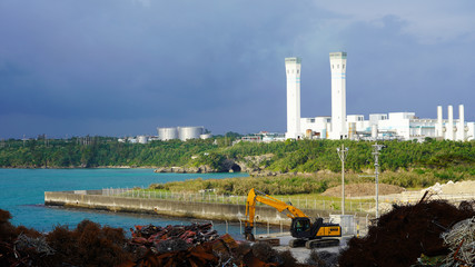 industrial landscape on a tropical island. scrap metal dump on the background of a large factory on the ocean. Ecological problem of humanity. ocean pollution