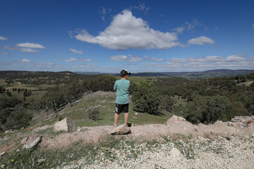 Obraz premium Boy standing on rocky cliff edge admiring view of landscape below
