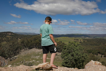 Young boy standing on cliff edge admiring view of the landscape below