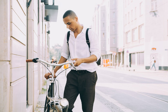 Businessman holding bicycle while standing on sidewalk in city