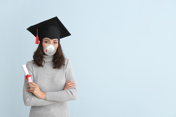 Female graduating student wearing protective mask on light background. Concept of epidemic