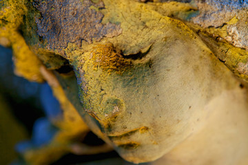 Close up an atcient stone statue of angel with sad expression.