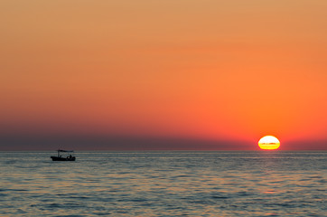 sunset over the sea with a lonely boat, mediterranean sea