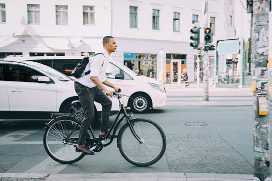 Full length of businessman riding bicycle on sidewalk against building in city