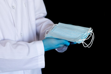 The nurse is counting medical masks. The nurse's glove hand puts medical masks on a black table and counts the number of medical masks