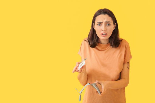 Sad young woman with empty wallet on color background