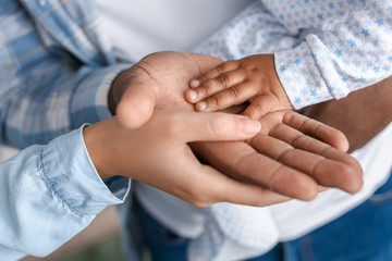 Hands of African-American parents and cute baby, closeup