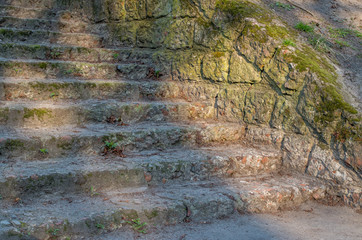 Embedded in a grassy earthen rampart, an ancient staircase consists of low, chipped steps made of...