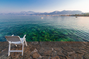 symbol of loneliness, lonely chair in the Crete island beach in sunset time. Greece vacation, copy space.