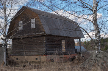 Old wooden house in village on sunny day in early spring