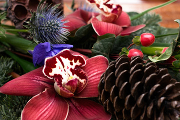 Winter bouquet of cymbidium, eringium,hypericum,nobilis,iris,cones and dry Lotus inflorescence on...