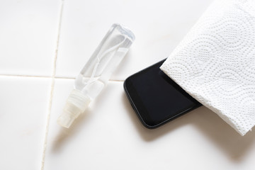 Cleaning smartphone with disinfectant in spray bottle on white background