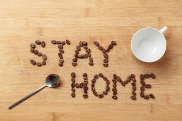 Stay Home slogan of roasted coffee beans, a spoon, an empty white porcelain cup