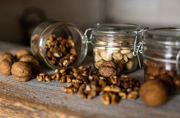 Walnut scattered on the white vintage table from a jar whith a whole walnuts. Walnut is a healthy vegetarian protein nutritious food. Walnut kernels and whole walnuts on rustic old wood.