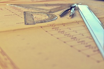Electrical engineer workplace - electrotechnical project, rulers, and divider compass. Construction and electrotechnology concept. Engineering tools. Circuit diagram on background. Retro haze.