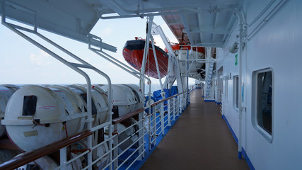 deck of a ship sailing on the sea. cruise liner walking deck. lifeboats, rafts and lifebuoys on the deck of the liner. safety signs on board ship. Pacific Ocean waves stormy