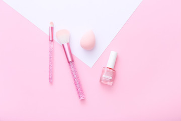 Female tools and makeup accessories on pink and white background.
