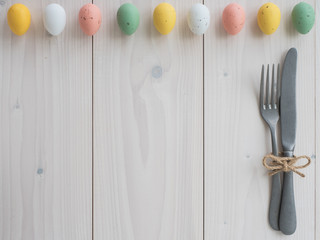 easter eggs and vintage cutlery on wooden board. table set