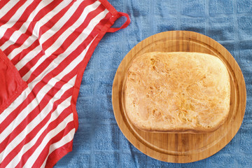 Freshly baked bread loaf and apron. Top down view.