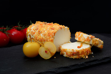 Homemade goat cheese with apples and tomatoes. Black background