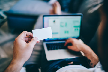 Man looking at business card working with laptop